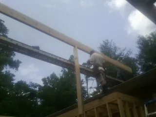 Carpenter setting a ridge beam over a new addition frame — Ice Dam Removal by Roofing Brothers in Remsen