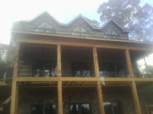 Dormers and porch framing on a large log home under construction — Roof Coating work by our crew in Remsen