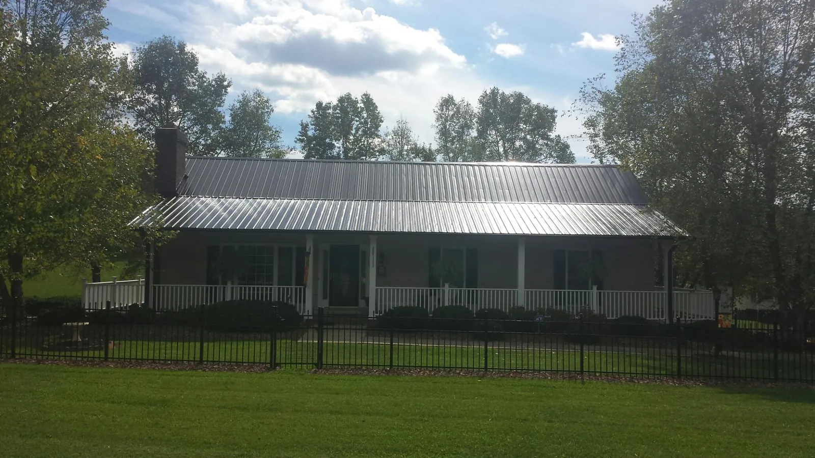Gray metal roof on a brick ranch with a full width front porch — Gutter Guard Installation work by our crew in Remsen